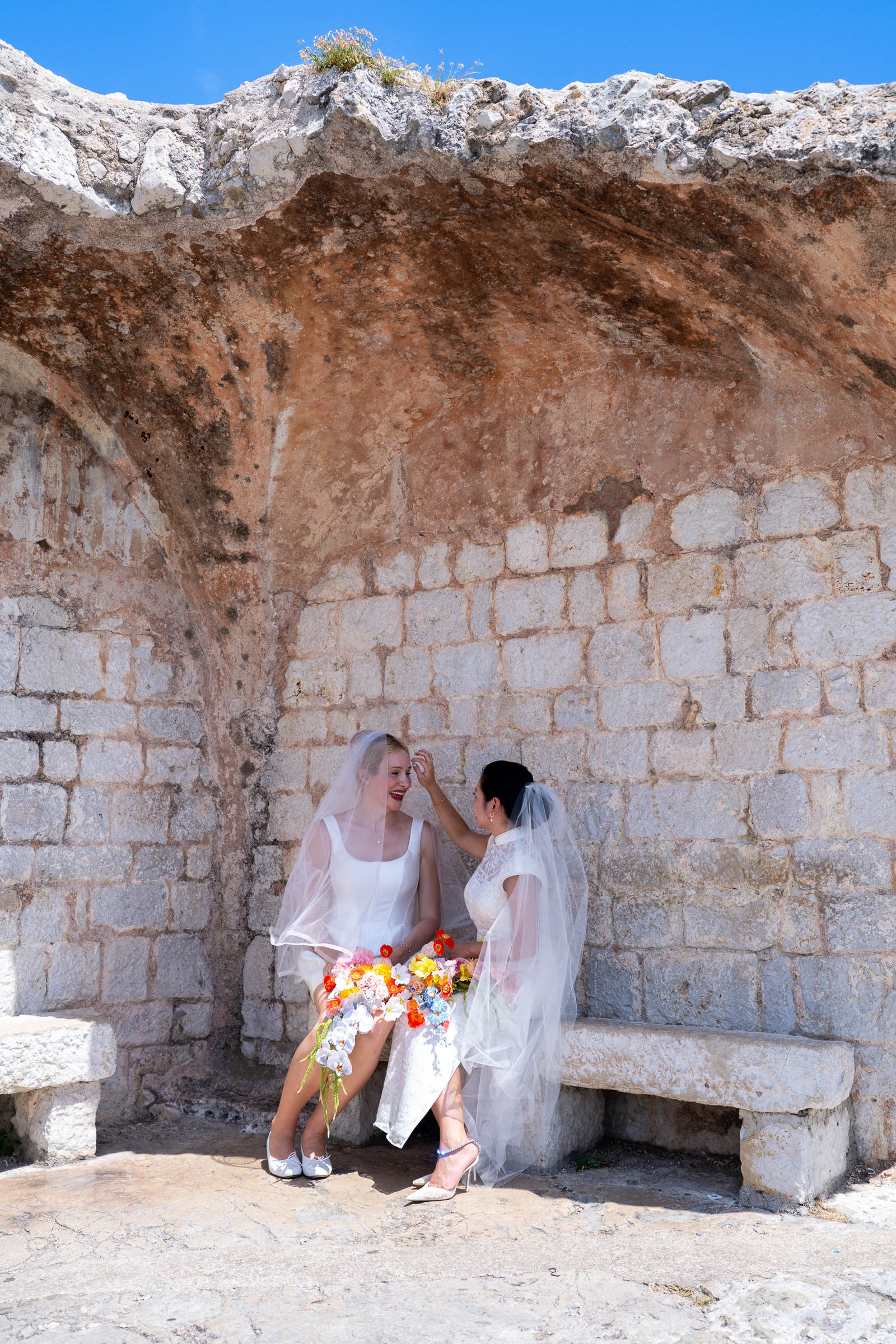 D and M seated together beneath a stone arch