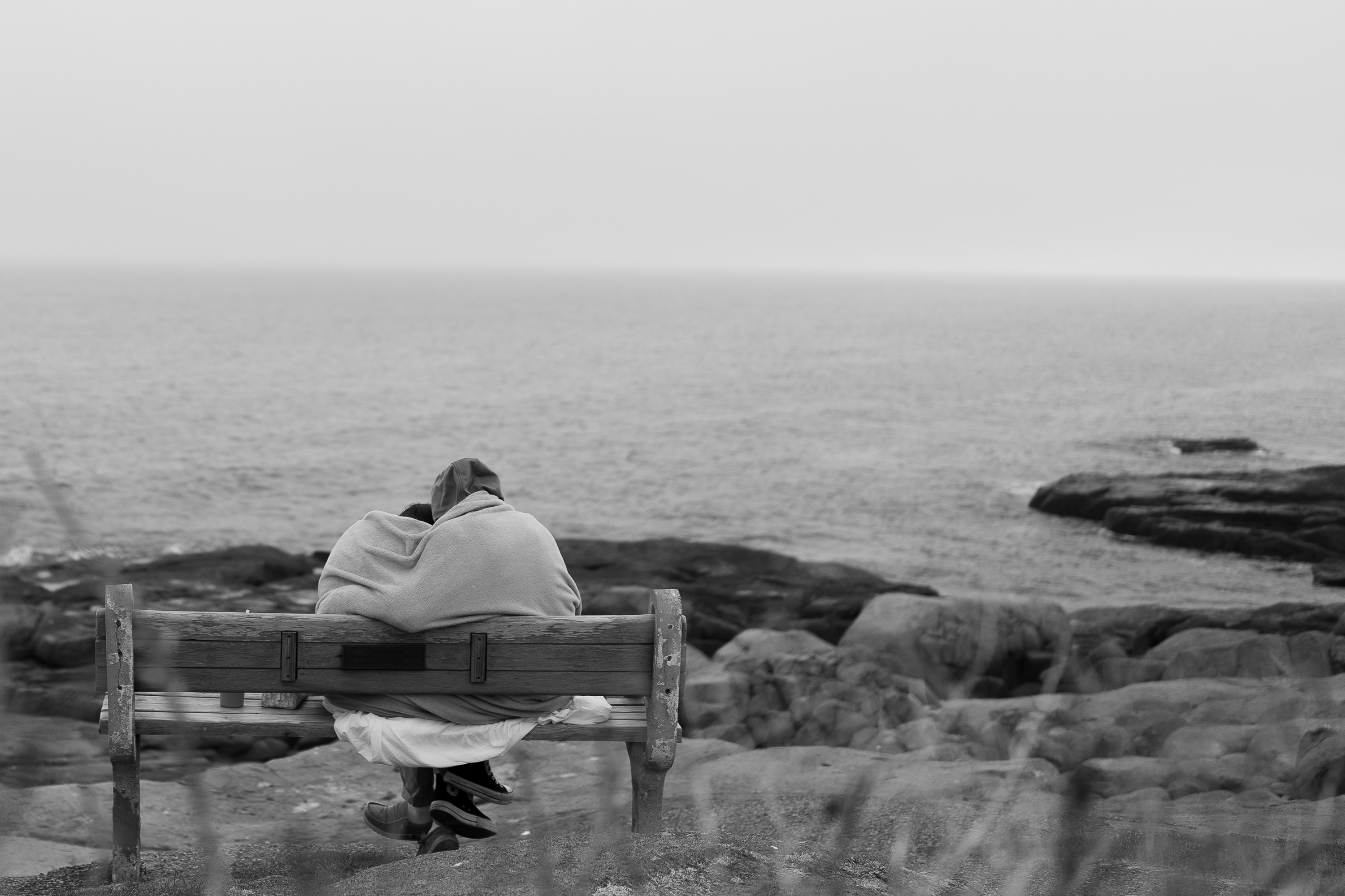 A person sitting on a bench overlooking the ocean